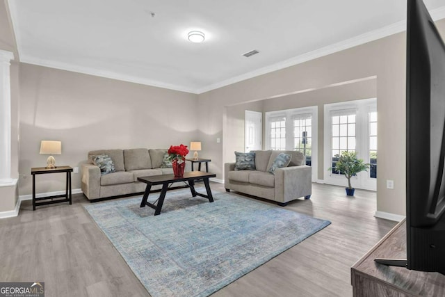 living room with baseboards, crown molding, visible vents, and wood finished floors