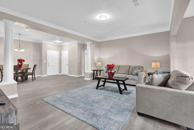 living room featuring baseboards, visible vents, decorative columns, and wood finished floors