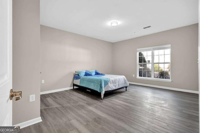 bedroom with baseboards, visible vents, and wood finished floors