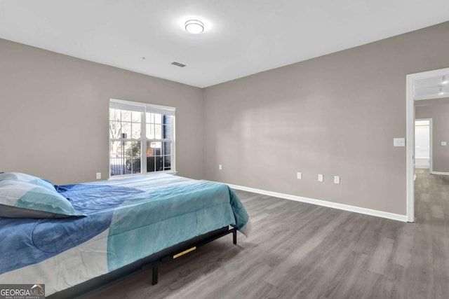bedroom featuring baseboards, visible vents, and wood finished floors