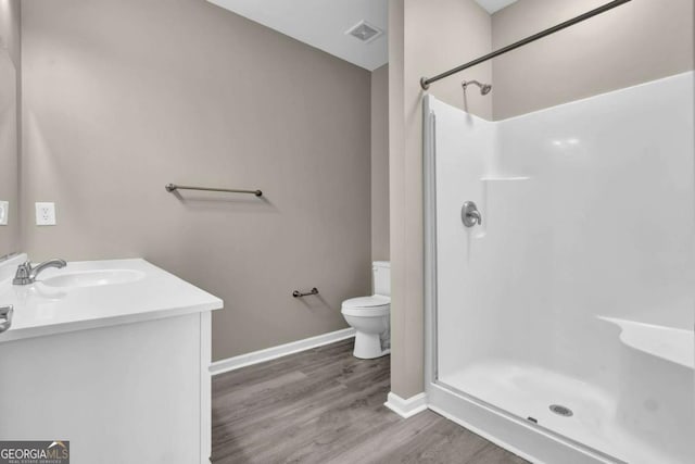 full bathroom with a stall shower, baseboards, toilet, visible vents, and wood finished floors