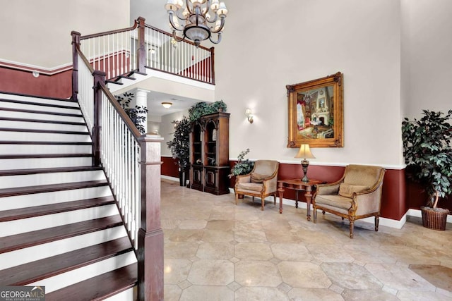 foyer entrance with stairway, an inviting chandelier, a high ceiling, and baseboards