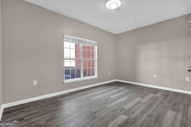 unfurnished room featuring dark wood-style flooring and baseboards