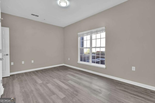 spare room with visible vents, wood finished floors, and baseboards