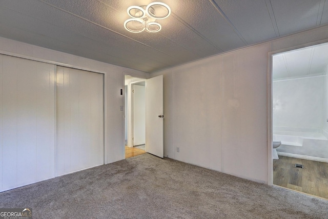 unfurnished bedroom with ensuite bath, carpet, and a closet