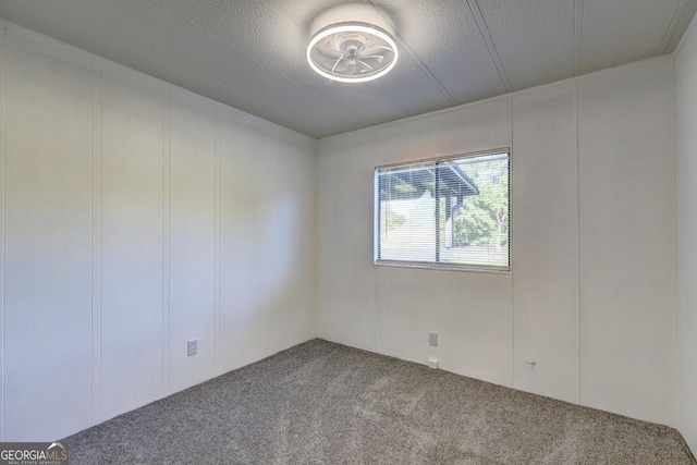 carpeted empty room with a decorative wall and a textured ceiling