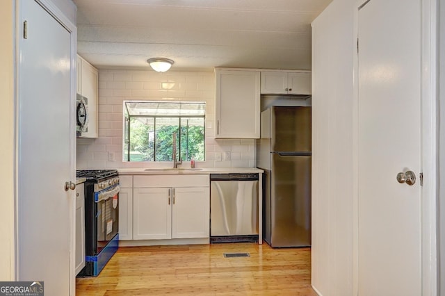 kitchen with white cabinets, decorative backsplash, stainless steel appliances, and a sink