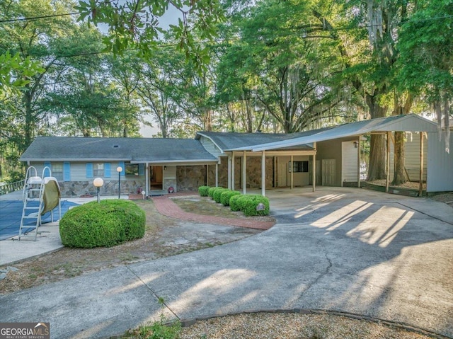 view of front of house featuring concrete driveway, stone siding, and an attached carport