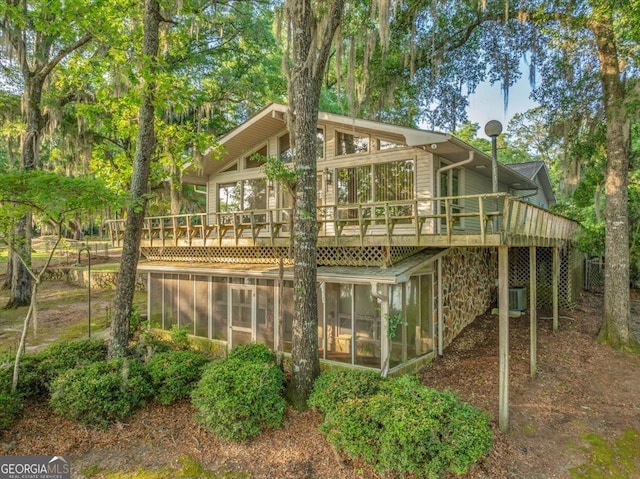 rear view of property featuring central AC unit, a sunroom, and a wooden deck