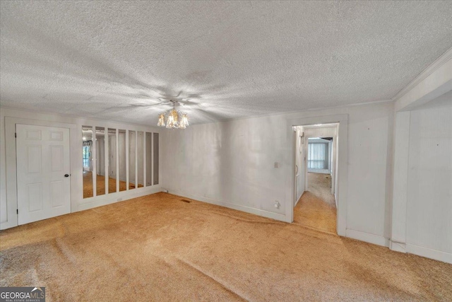 spare room with a textured ceiling, carpet, a notable chandelier, and baseboards