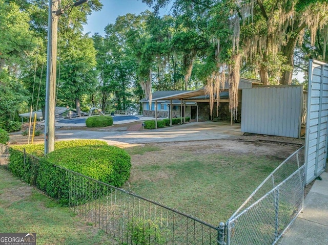 view of home's community featuring concrete driveway, a detached carport, and fence