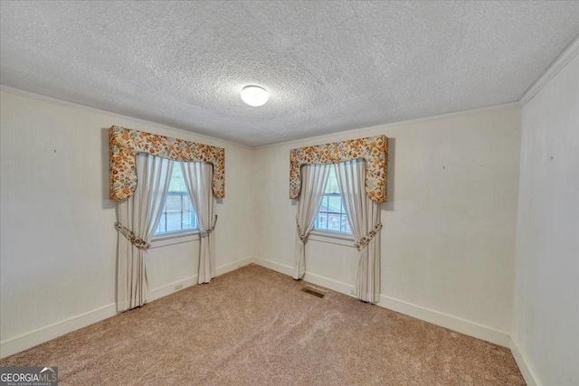 empty room featuring a healthy amount of sunlight, light colored carpet, a textured ceiling, and visible vents