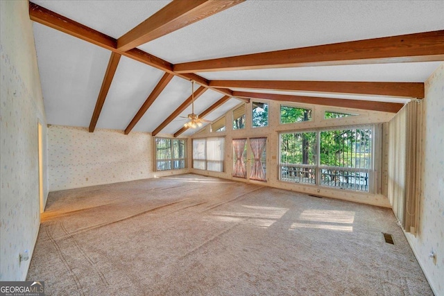 unfurnished living room featuring a ceiling fan, wallpapered walls, carpet flooring, visible vents, and lofted ceiling with beams