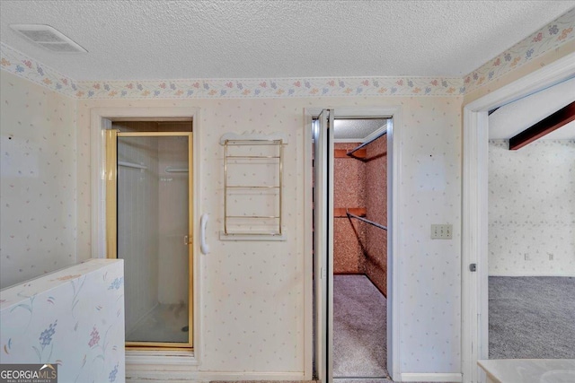 full bathroom with a textured ceiling and wallpapered walls