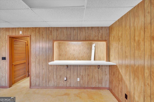 room details with a drop ceiling and wood walls