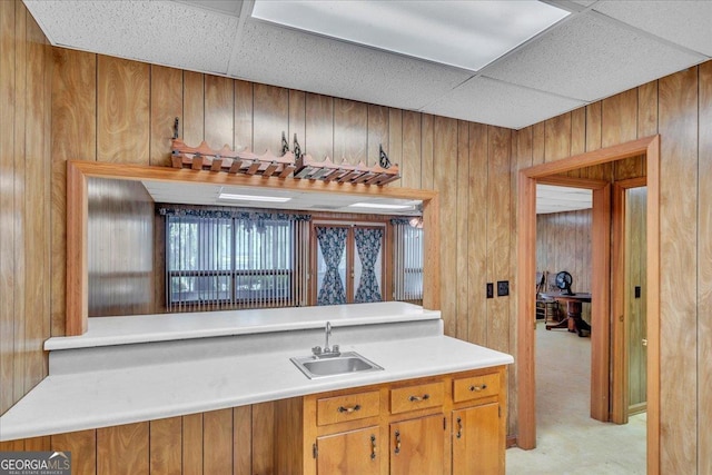 bar featuring a sink, wooden walls, and a paneled ceiling