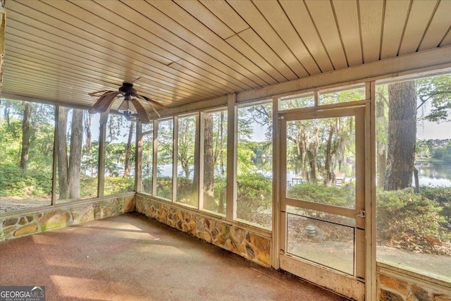 unfurnished sunroom with a ceiling fan, a water view, and plenty of natural light