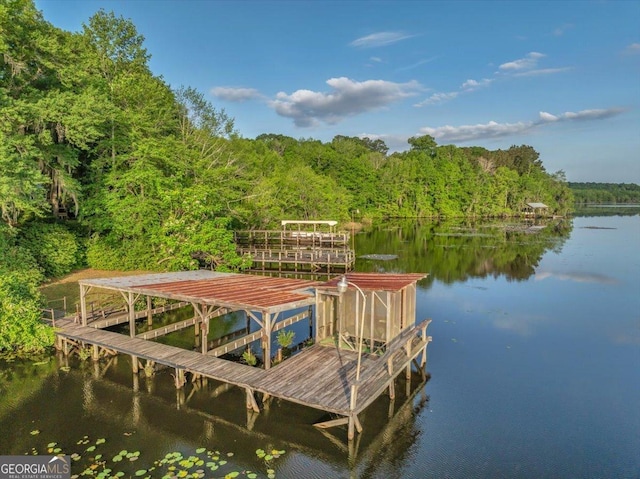 view of dock featuring a forest view and a water view