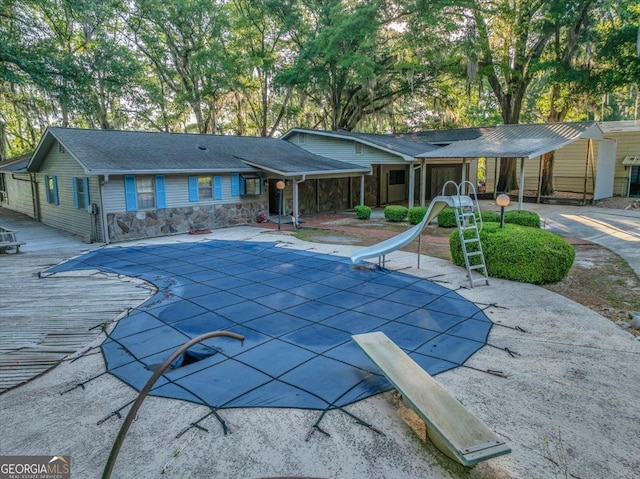 view of pool with a diving board, a water slide, a covered pool, and a patio area