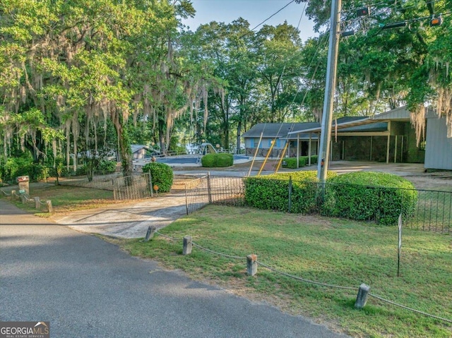view of community featuring a yard, driveway, and fence