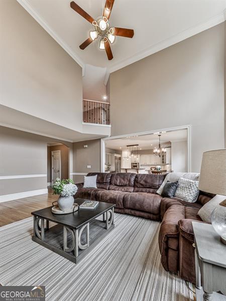 139 Grandmar Chase, Canton, GA 30115 - living room featuring wood finished floors, ceiling fan with notable chandelier, crown molding, baseboards, and a towering ceiling