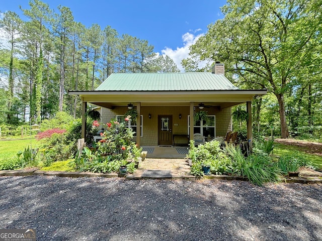 view of front of property featuring a ceiling fan, a chimney, and metal roof