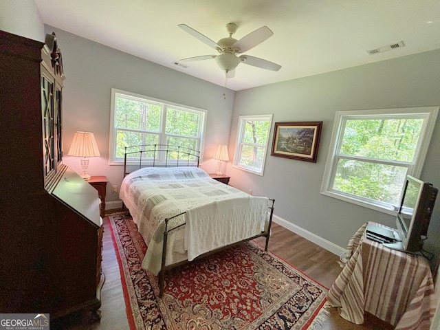 bedroom with wood finished floors, visible vents, baseboards, and ceiling fan