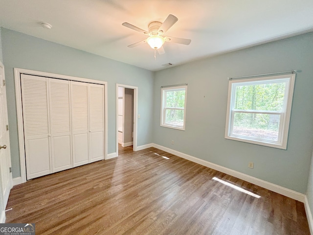 unfurnished bedroom featuring a closet, wood finished floors, visible vents, ceiling fan, and baseboards