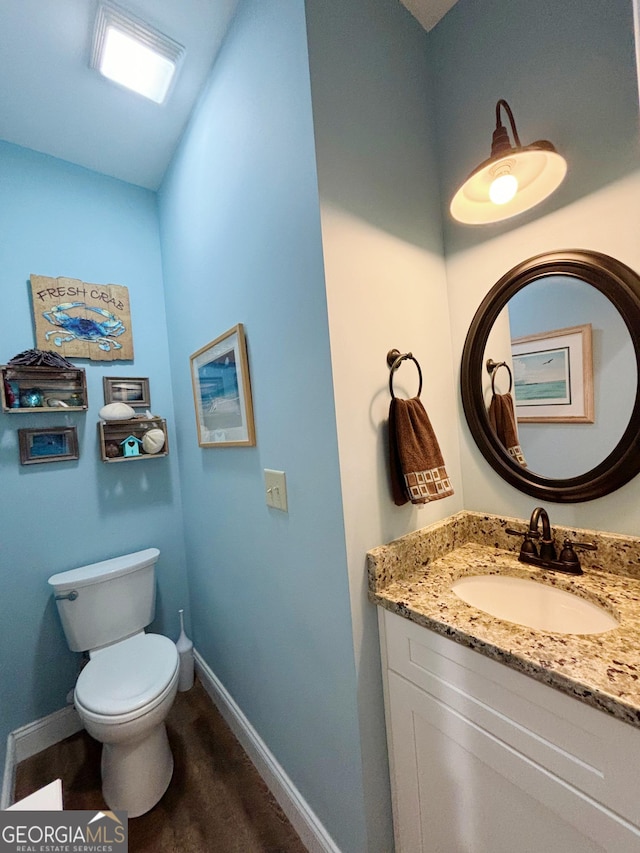 half bath with vanity, toilet, and baseboards