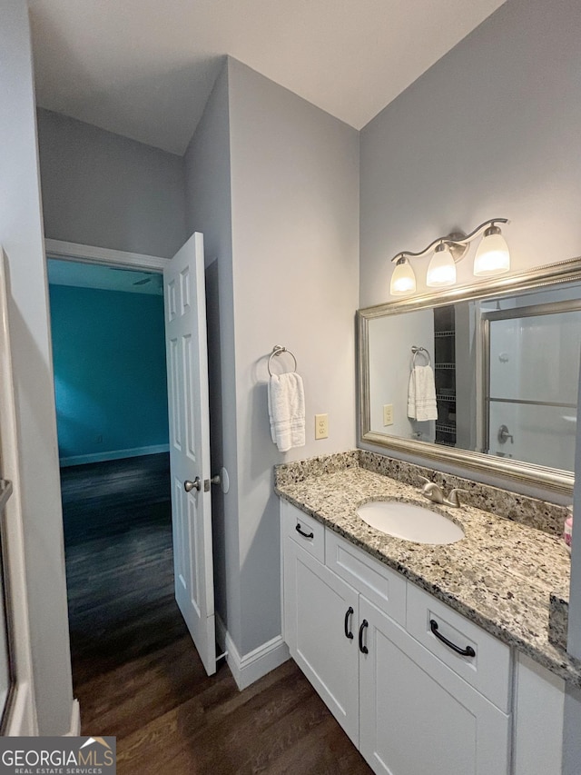 full bath with vanity, baseboards, a shower, and wood finished floors