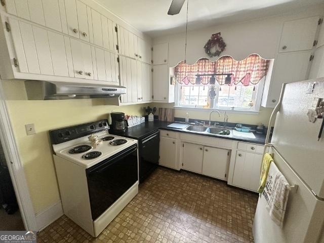327 W Church St, Swainsboro, GA 30401 - kitchen with under cabinet range hood, white appliances, a sink, dark countertops, and white cabinets