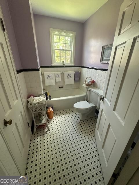 327 W Church St, Swainsboro, GA 30401 - bathroom with a wainscoted wall, a bathing tub, tile walls, and toilet