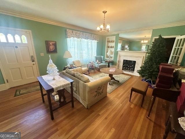 327 W Church St, Swainsboro, GA 30401 - living room with an inviting chandelier, wood finished floors, a fireplace with flush hearth, and crown molding