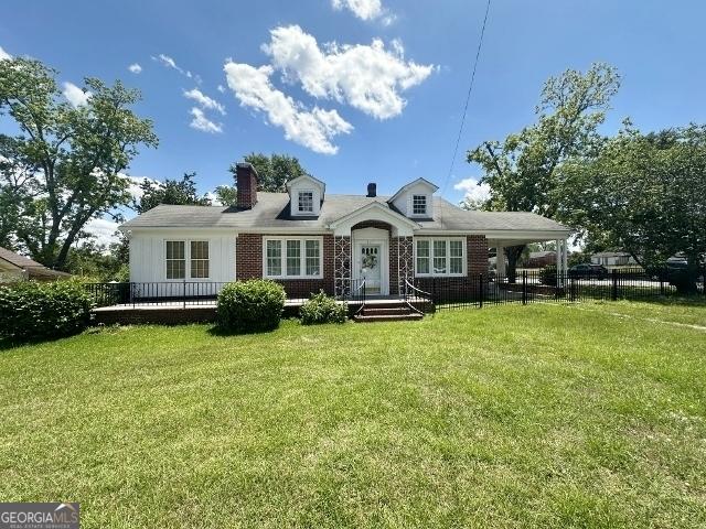 327 W Church St, Swainsboro, GA 30401 - view of front of home featuring a chimney, a front yard, fence, and a carport