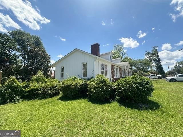 327 W Church St, Swainsboro, GA 30401 - view of home's exterior featuring a lawn, board and batten siding, and a chimney