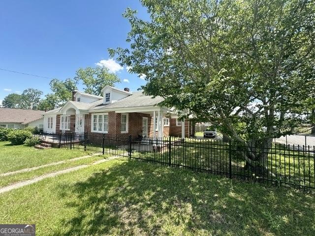 327 W Church St, Swainsboro, GA 30401 - view of front of house with brick siding, a front lawn, and fence private yard