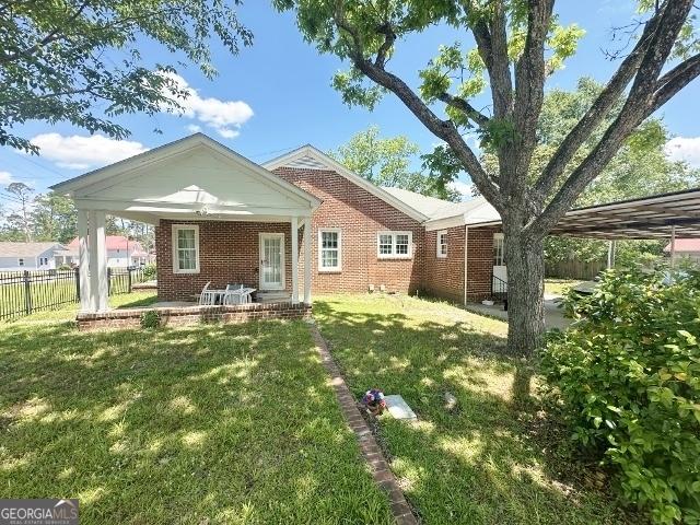 327 W Church St, Swainsboro, GA 30401 - rear view of property featuring a yard, fence, and brick siding