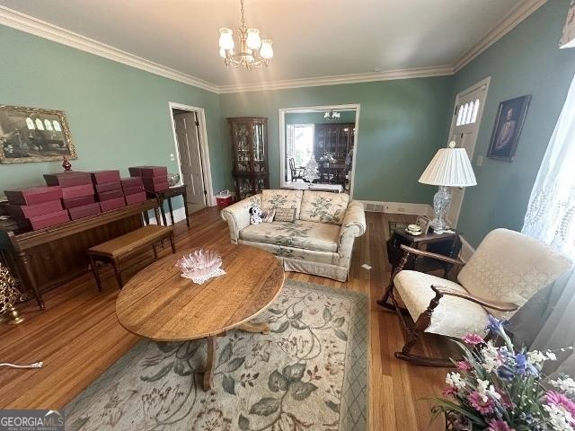 327 W Church St, Swainsboro, GA 30401 - living room featuring a chandelier, wood finished floors, and ornamental molding