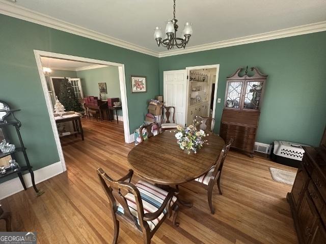 327 W Church St, Swainsboro, GA 30401 - dining space featuring baseboards, ornamental molding, visible vents, a chandelier, and wood finished floors