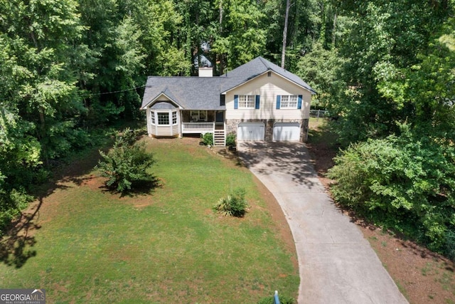 split level home featuring covered porch, a garage, a chimney, concrete driveway, and a front yard