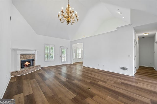4368 Magnolia Bay Ln, Snellville, GA 30039 - unfurnished living room with wood finished floors, high vaulted ceiling, baseboards, a brick fireplace, and a notable chandelier