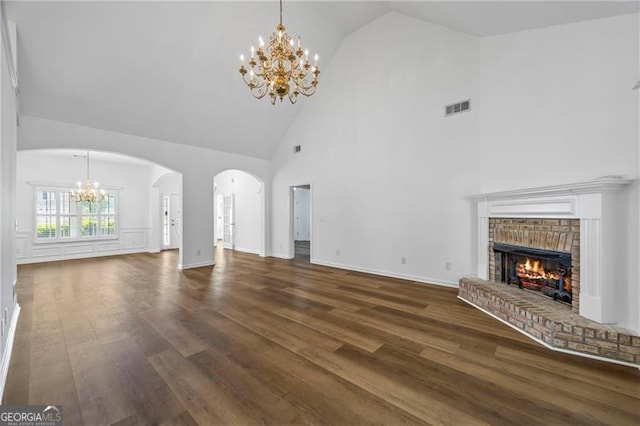 4368 Magnolia Bay Ln, Snellville, GA 30039 - unfurnished living room featuring high vaulted ceiling, visible vents, dark wood-type flooring, arched walkways, and a notable chandelier