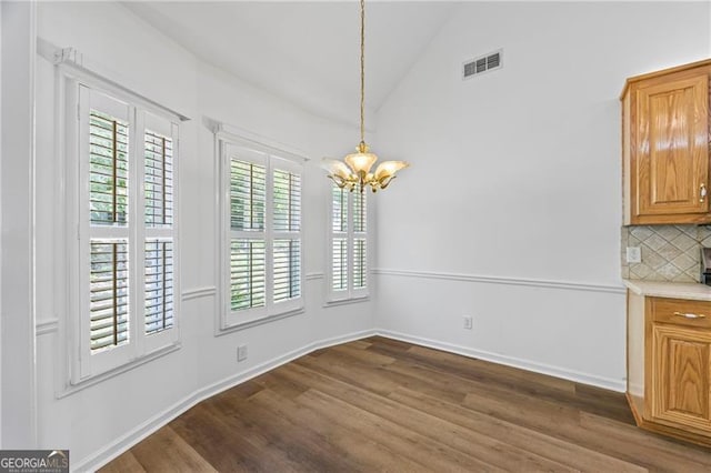 4368 Magnolia Bay Ln, Snellville, GA 30039 - unfurnished dining area featuring an inviting chandelier, visible vents, baseboards, lofted ceiling, and dark wood-style floors