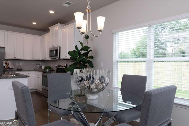 dining area with dark wood finished floors, a notable chandelier, visible vents, and recessed lighting
