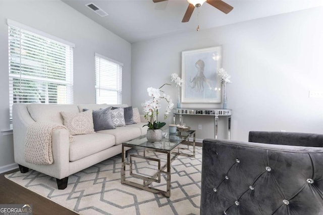 living area with a ceiling fan, baseboards, visible vents, and wood finished floors