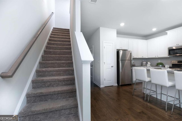 staircase with wood finished floors, baseboards, and recessed lighting
