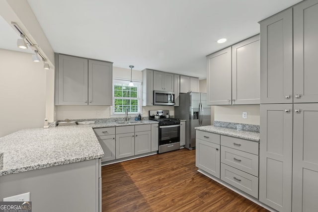 kitchen featuring a sink, gray cabinets, dark wood finished floors, light stone countertops, and appliances with stainless steel finishes
