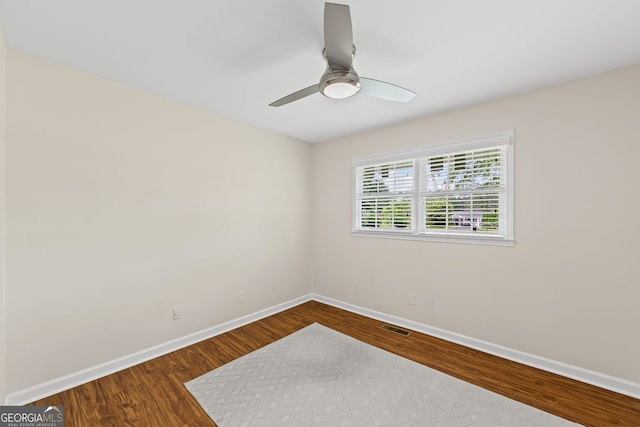 spare room featuring dark wood-style flooring, baseboards, a ceiling fan, and visible vents