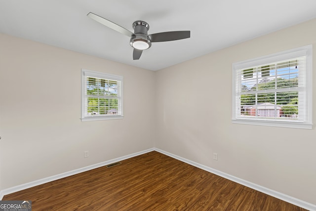 empty room with baseboards, ceiling fan, visible vents, and dark wood-style floors