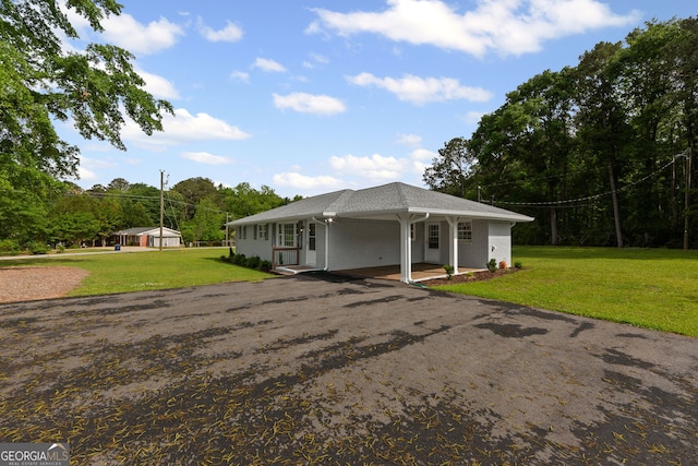 back of house with covered porch, a carport, aphalt driveway, a yard, and brick siding